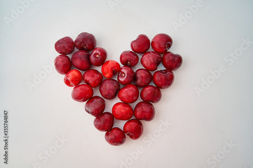 Heart made with cherries, summer seasonal fruit, on white background