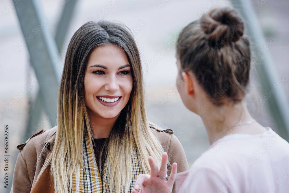 two young women talking and smiling about something