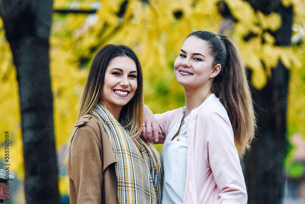two women posing for pictures on a beautiful autumn day two women posing for pictures on a beautiful autumn day