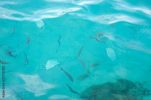 Masque chirurgical dans de l'eau de mer au milieu des poissons