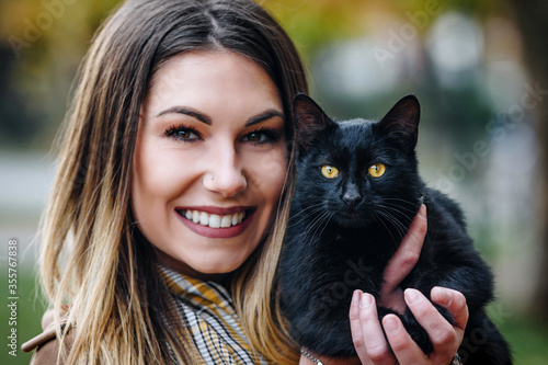 young woman smiling and holding her black cat