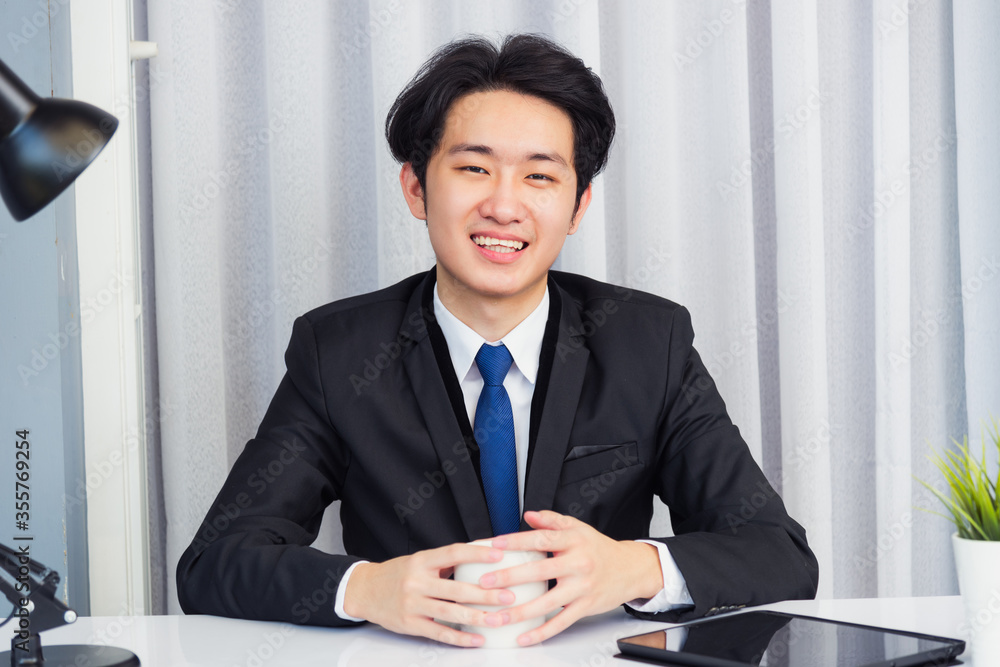 Work from home, Asian young businessman video conference call or facetime he smiling looking to camera sitting with hands on desk using smart digital tablet computer at home office Work from home, Asian young businessman video conference call or facetime he smiling looking to camera sitting with hands on desk using smart digital tablet computer at home office