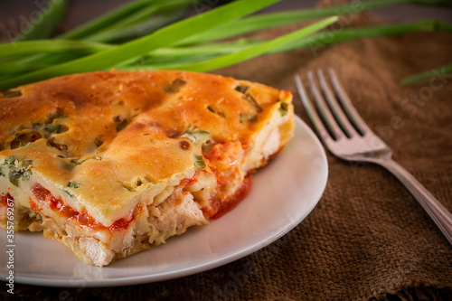 Homemade pie with chicken, herbs and tomatoes on a plate.