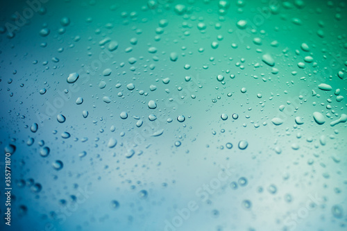 water drops on glass window, green and blue background