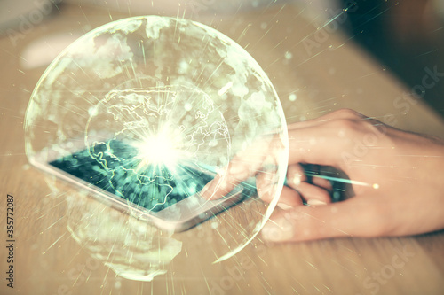 Double exposure of business theme sketch hologram and woman holding and using a mobile device.