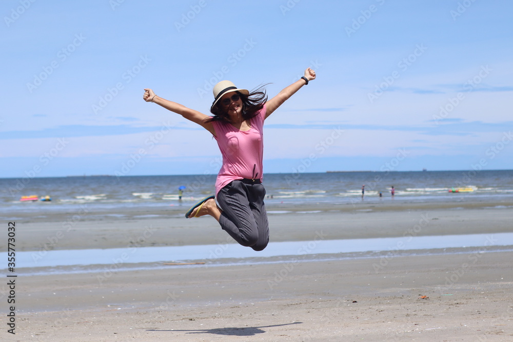 Asian women wearing pink shirts and wooden hats are jumping with joy and freshness. On the beach on a summer holiday Summer concept Asian women wearing pink shirts and wooden hats are jumping with joy and freshness. On the beach on a summer holiday Summer concept