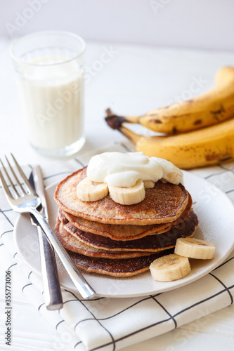 Banana pancakes with whole wheat flour on white background, bananas, yogurt and glass of milk. Healthy breakfast, breakfast concept, morning concept