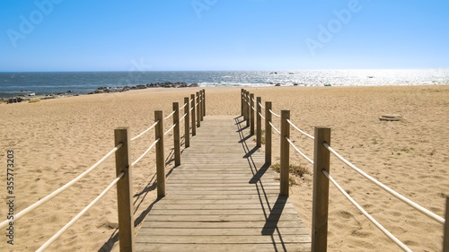 Wooden walkway over sand dunes to beach on a bright sunny day in summer with blue sky
