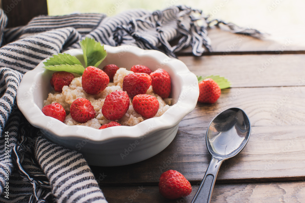 Breakfast. Tasty oatmeal with berries. Healthy breakfast ingredients. Oat granola in bowl with strawberry and mint. Granola for breakfast with berries.