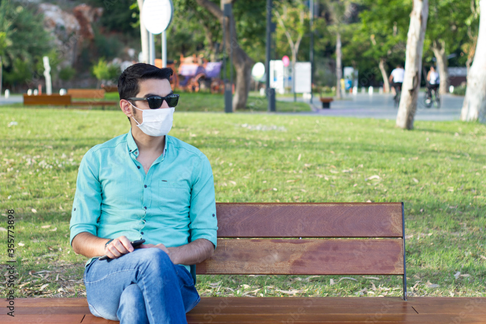 Fototapeta premium man in medical mask is sitting on a bench on the street during quarantine