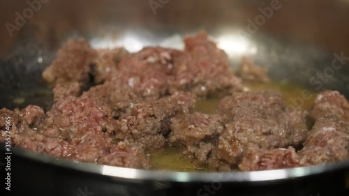 Ground beef cooking in a frying pan with a pool of fat.