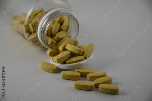 Yellow pills in transparent container with a white background