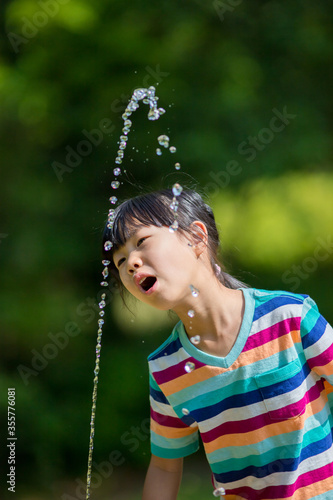 真夏の公園で水を飲む可愛い子供