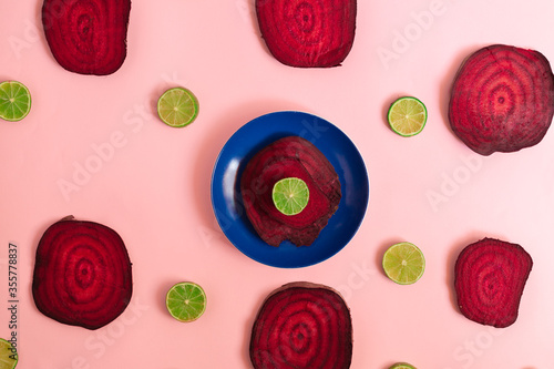 Beetroot in the form of a pattern with lemon slices on a pink background