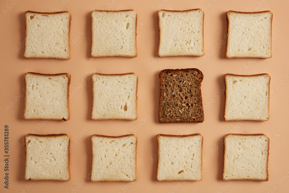 Set of white and wholegrain bread slices on light beige background. Rectangular pieces of bread made of organic flour, one is dark prepared for toasting. Top view from above, flat lay. Pastry food. Set of white and wholegrain bread slices on light beige background. Rectangular pieces of bread made of organic flour, one is dark prepared for toasting. Top view from above, flat lay. Pastry food.