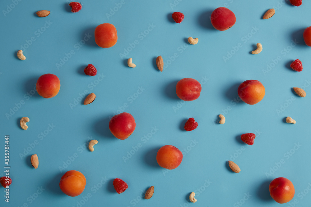 Set of ripe peaches, raspberry, cashew and almond nuts on blue background. Ingredients for tasty quick snack or preparing breakfast. Healthy source of vitamins. Vegetarian food. Selective focus Set of ripe peaches, raspberry, cashew and almond nuts on blue background. Ingredients for tasty quick snack or preparing breakfast. Healthy source of vitamins. Vegetarian food. Selective focus