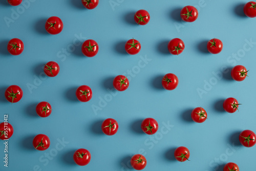 Healthy eating, organic vegetables for vegetarians, agriculture concept. Fresh ripe red tomatoes with green stems on blue background. Harvested cropes for making juice sauces or salad. Nutrition, food