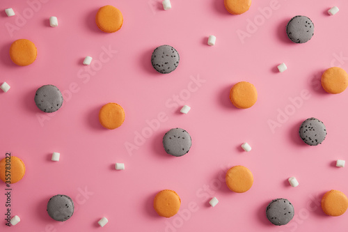 Set of orange and coffee flavored macaroons with appetizing marshmallow isolated on pink background. Small french cakes. Delicious homemade cookies for sweet tooth. View from above. Macarons banner