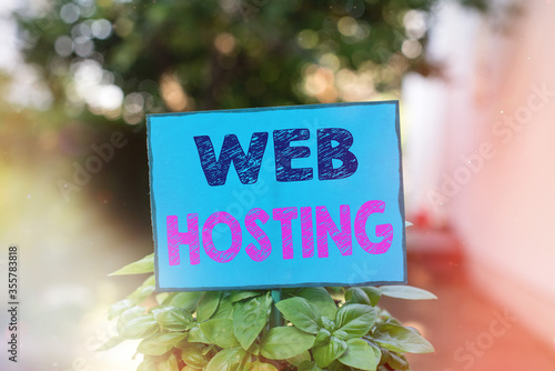 Text sign showing Web Hosting. Business photo text business allowing access to a server to store data in a website Plain empty paper attached to a stick and placed in the green leafy plants photo