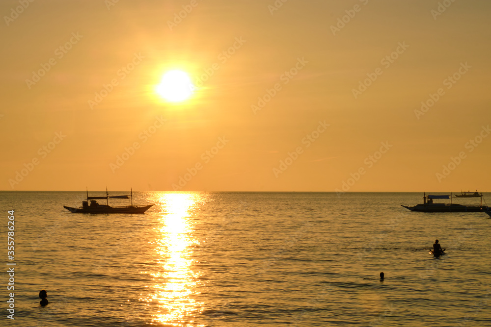 Boracay, Philippines - Jan 27, 2020: Sunset on Boracay island. Sailing and other traditional boats with tourists on the sea against the background of the setting sun.