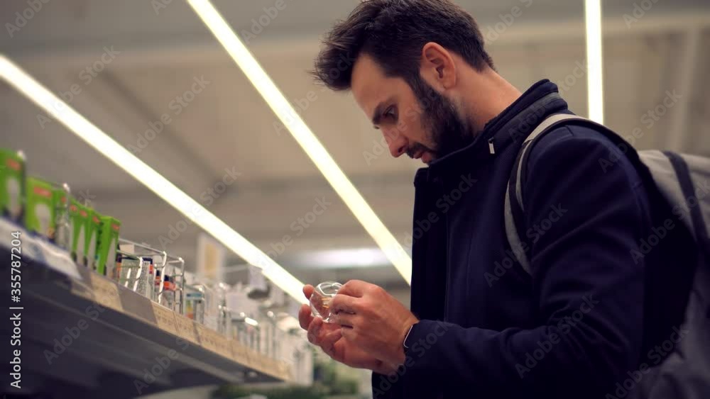 Man In Market Choosing Led Lamp. Businessman In Supermarket.Shopping In Hypermarket Mall On Electronic Device Store Section.Bayer Guy Choose Lamp For Home. Customer Looking On Product In Consumer Shop Man In Market Choosing Led Lamp. Businessman In Supermarket.Shopping In Hypermarket Mall On Electronic Device Store Section.Bayer Guy Choose Lamp For Home. Customer Looking On Product In Consumer Shop