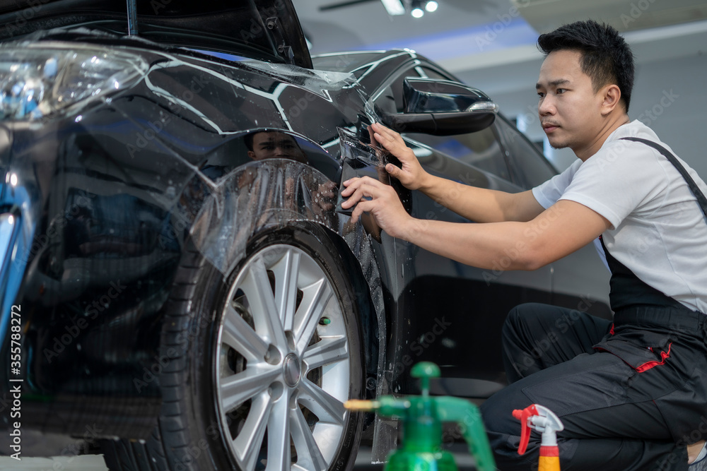 Obraz premium Car by putting vinyl foil or film on car. Selective focus. Car wrapping specialist putting vinyl foil or film on car. Selective focus.