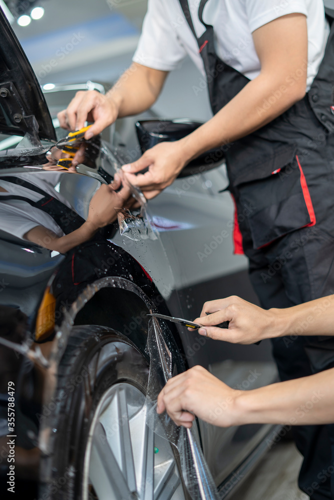 Obraz premium Car by putting vinyl foil or film on car. Selective focus. Car wrapping specialist putting vinyl foil or film on car. Selective focus.