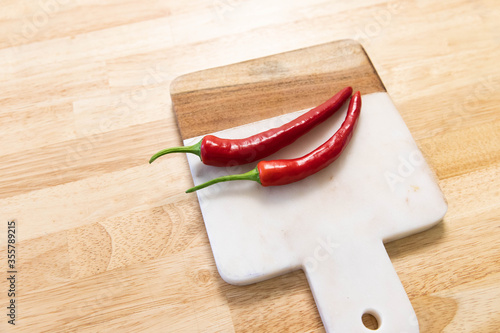 Red chilli on wooden cutting board. Wooden and marble stone material cutting board design.