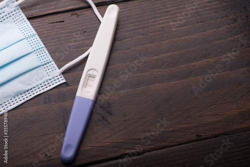 A pregnancy test kit with medical face mask,isolated over various background,conception during pandemic concept