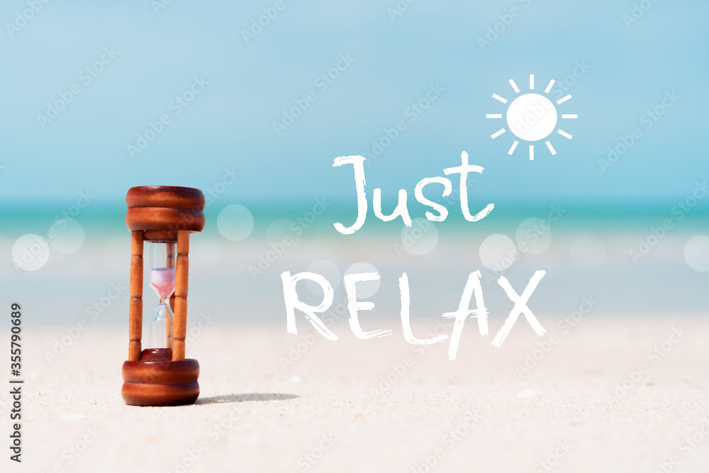 Just relax qoute with hourglass on sand and summer beach blue sky ...