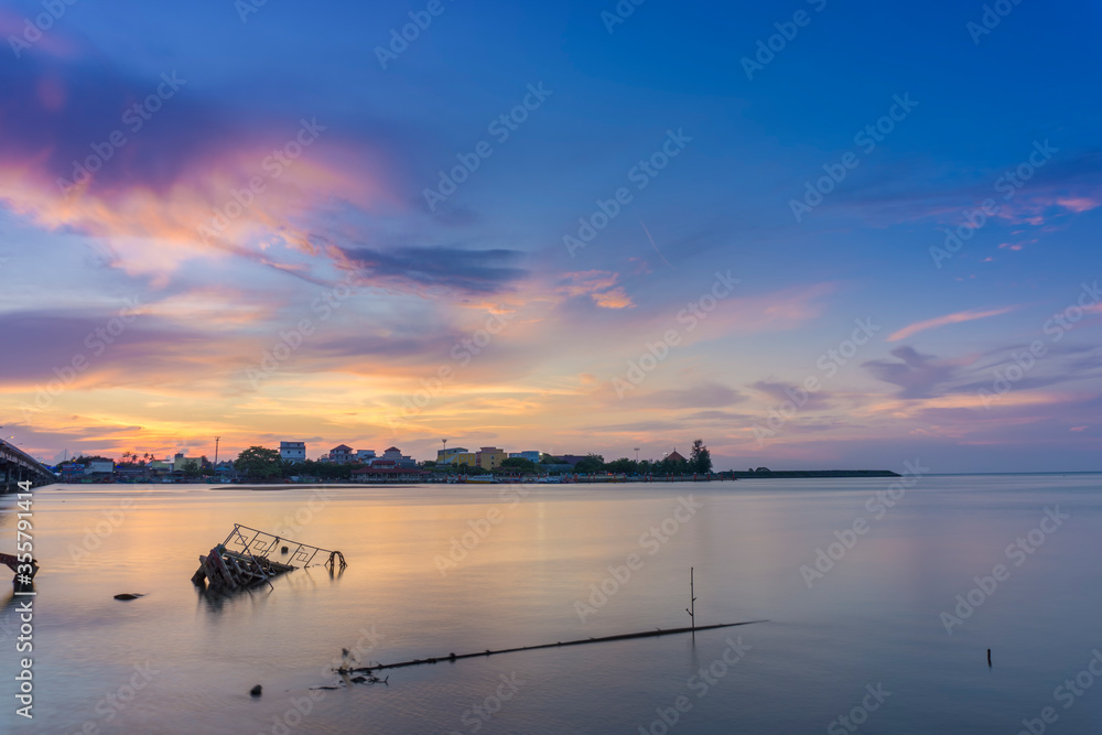Beautiful sunset scenery of a wooden fisherman boat with smooth clouds and smooth water surface, at Kelantan, Malaysia