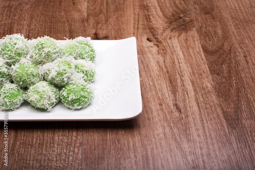 Traditional Malaysian,Indoensian and Singaporean cuisine known as Buah Melaka or Ondeh-ondeh,isolated over wooden background photo