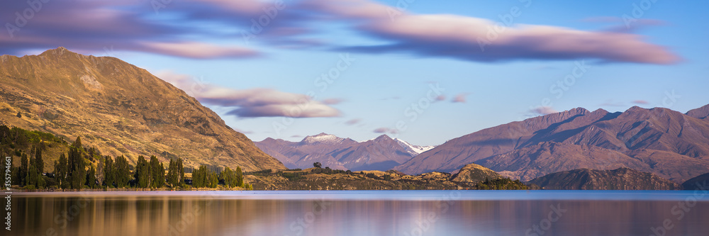 Fototapeta premium Mountain Lake Sunrise Landscape. Lake Wanaka New Zealand. Beautiful Morning Light Mountains Panorama Landscape Banner Background