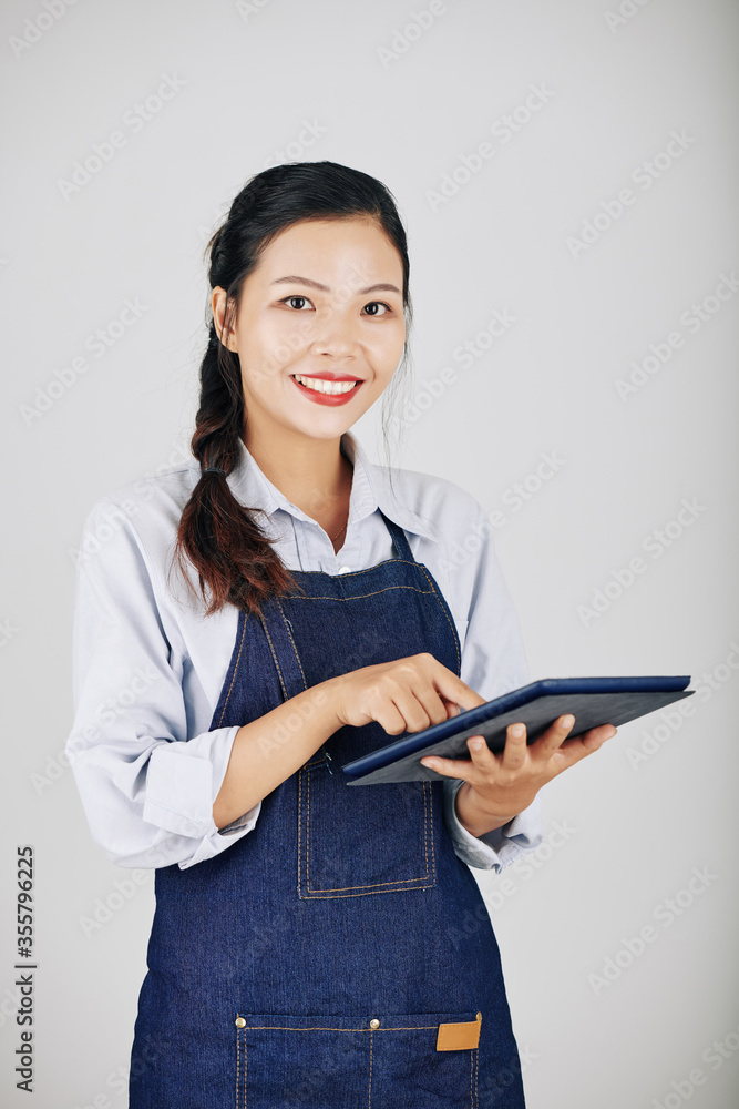 Portrait of smiling pretty Asian waitress using application on tablet computer when accepting order Portrait of smiling pretty Asian waitress using application on tablet computer when accepting order