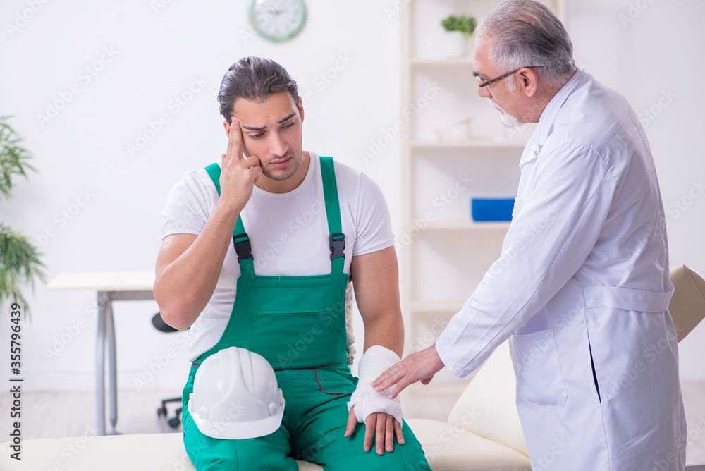 Fototapeta premium Young male contractor visiting old doctor