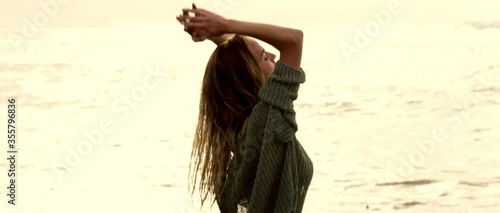 Warm sunrise on the black sand beach with sexy young woman girl posing very sexy and sensitive in swimwear and blouse middle angle