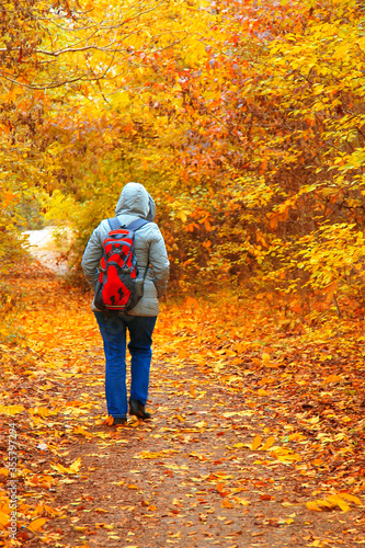 Young woman with bagpack walking in autumn park