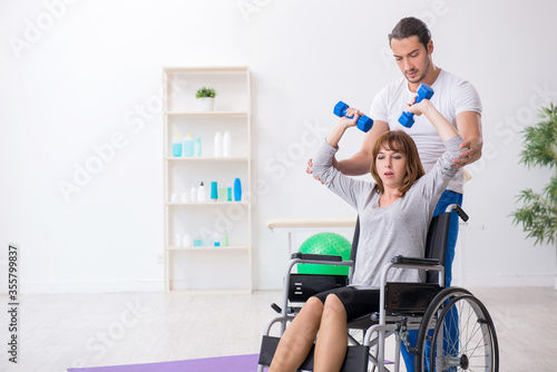 Woman in wheel-chair doing sport exercises with personal coach © Elnur