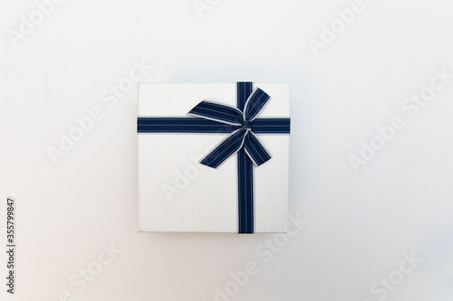 Top view image of white gift box with blue ribbon on a white background.