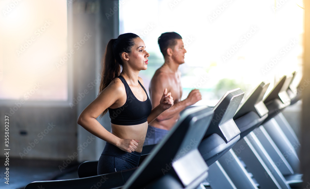 attractive young woman and female running on treadmill  machine at gym sports club. Fitness Healthy lifestye and workout at gym concept.