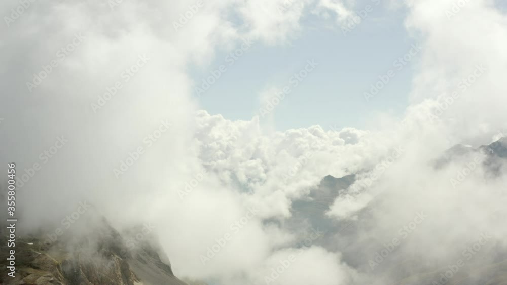 Aerial shot of clouds over mountains against sky on sunny day, drone flying over natural landscape - Swiss Alps, Switzerland Aerial shot of clouds over mountains against sky on sunny day, drone flying over natural landscape - Swiss Alps, Switzerland