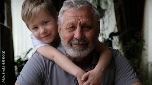 Senoir elderly happy man grandfather with grandson boy looking at camera, smiling and hugging photo