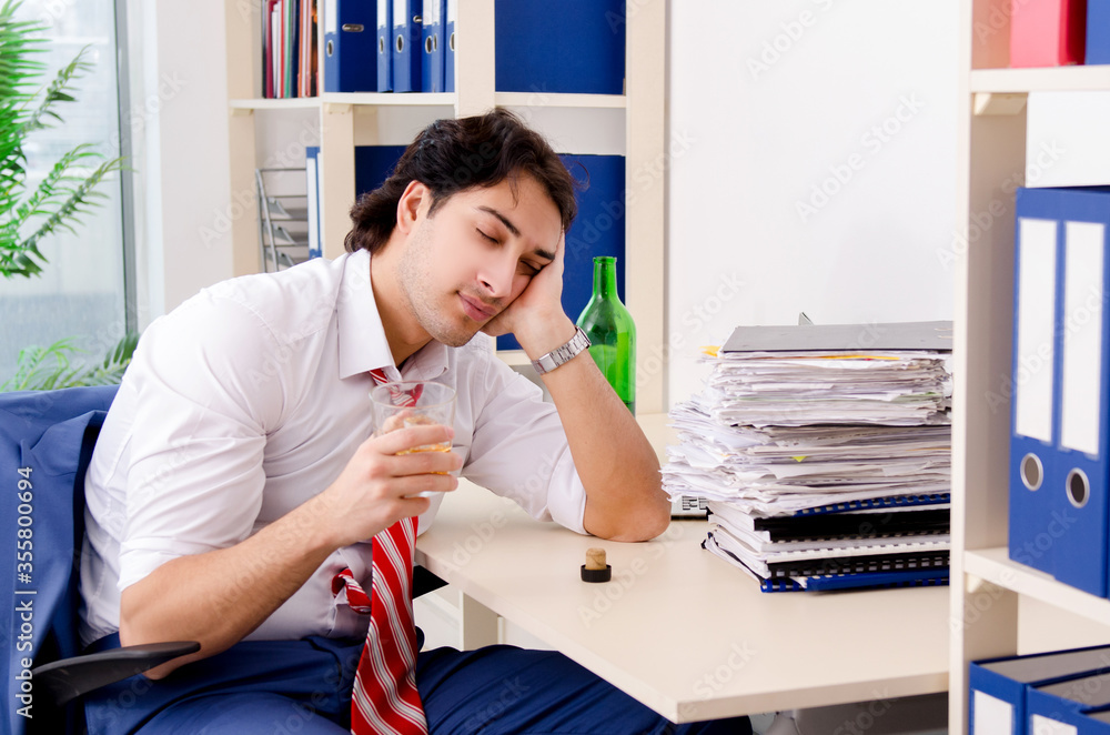 Fototapeta premium Young businessman employee drinking in the office