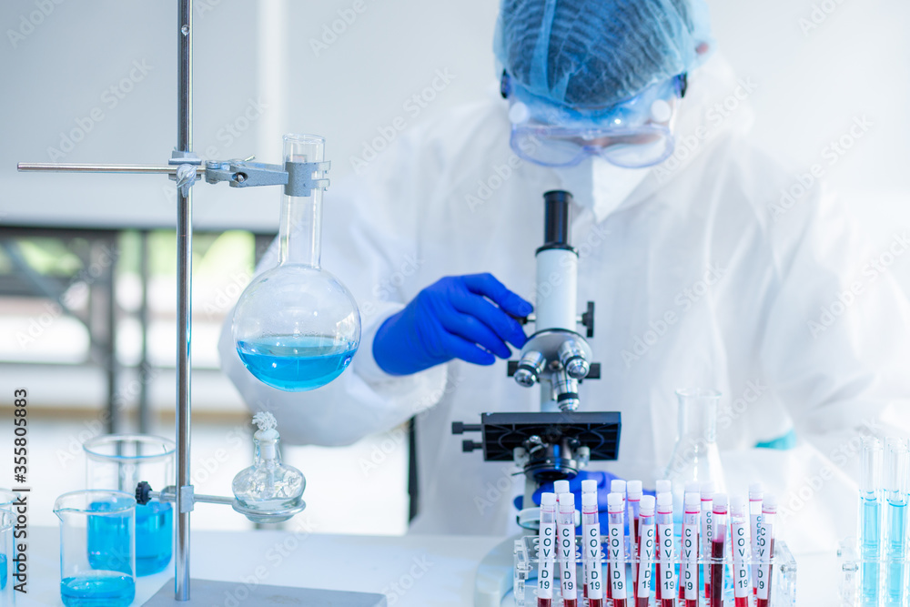 Scientist Working On Coronavirus Vaccine At Lab. Abstract of Analyzing covid 19 sample with microscope and holding coronavirus covid 19 blood sample tube in laboratory. Scientist Working On Coronavirus Vaccine At Lab. Abstract of Analyzing covid 19 sample with microscope and holding coronavirus covid 19 blood sample tube in laboratory.