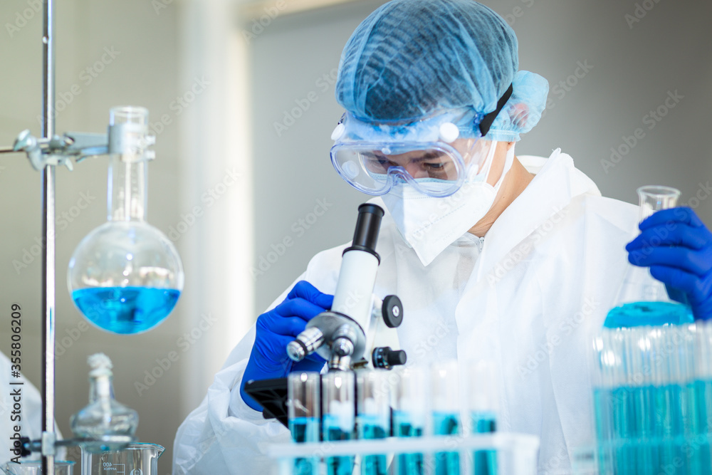 Scientist Working On Coronavirus Vaccine At Lab.
Abstract of Analyzing covid 19 sample with microscope and holding coronavirus covid 19 blood sample tube in laboratory.