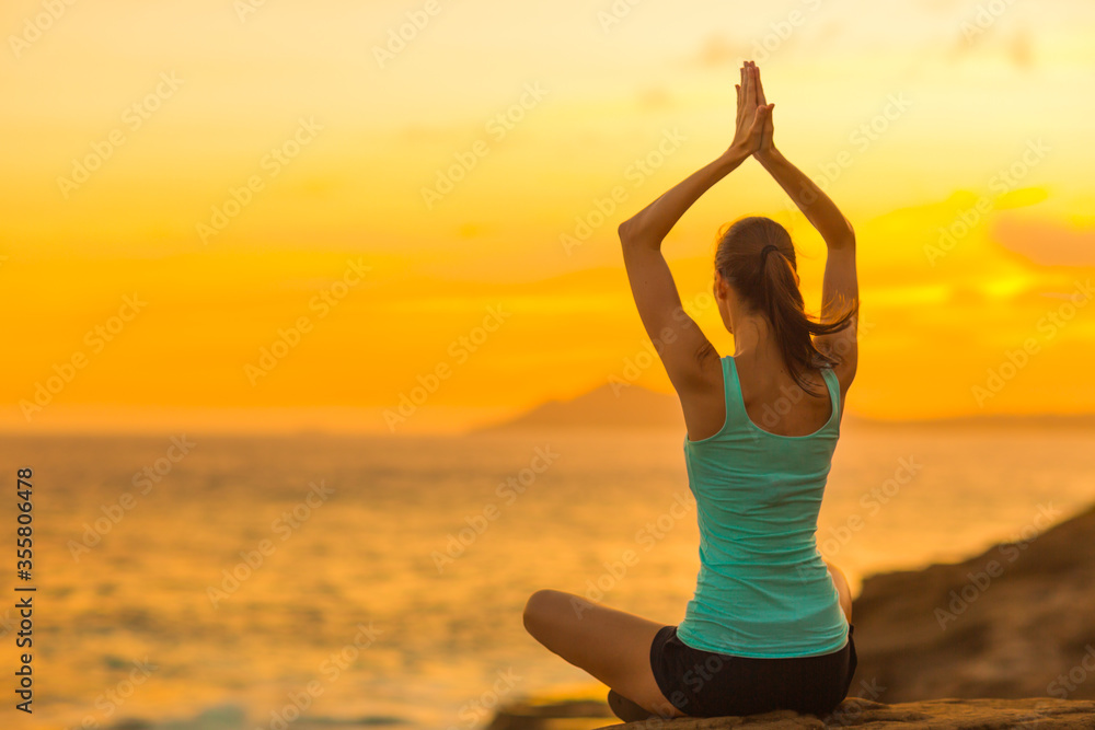 Healthy young woman doing yoga meditation exercise at the beach during a beautiful orange sunset in Hawaii. Body and mind wellness. Healthy young woman doing yoga meditation exercise at the beach during a beautiful orange sunset in Hawaii. Body and mind wellness.