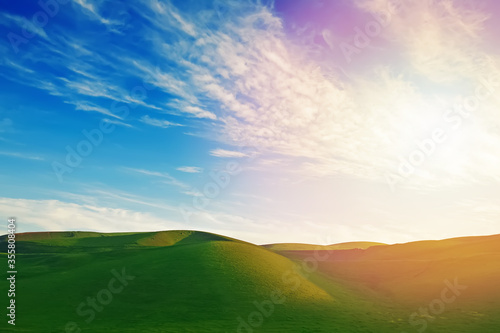 Green sloping meadows with blue sky
