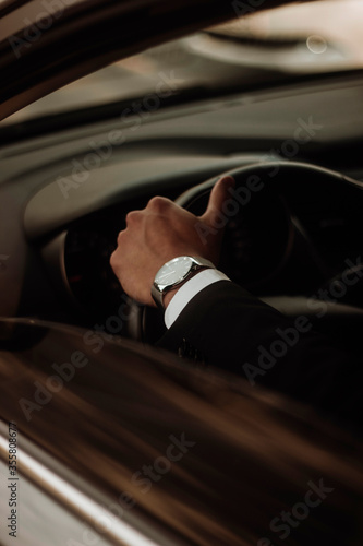 hand of a man with a clock in the car