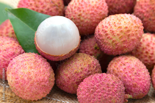 Pile of fresh lychee sweet fruit and peeled showing white fleshon on hemp sacks, Tropical fruits in thailand.