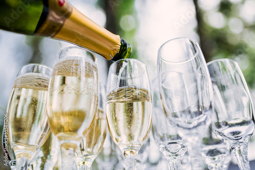 the waiter pours champagne in glasses on the street - wedding catering - look from below